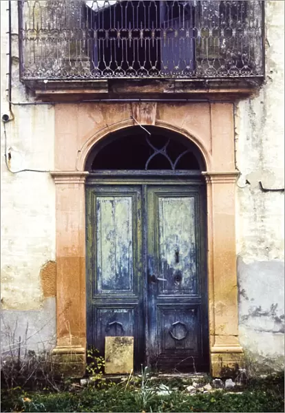 Crumbling, dilapidated entrance doorway and balcony of old French maison de maitre