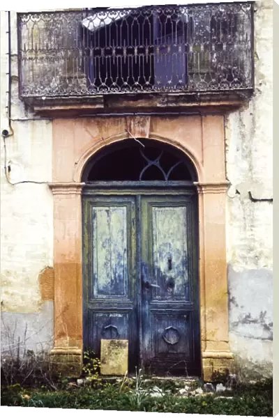 Crumbling, dilapidated entrance doorway and balcony of old French maison de maitre
