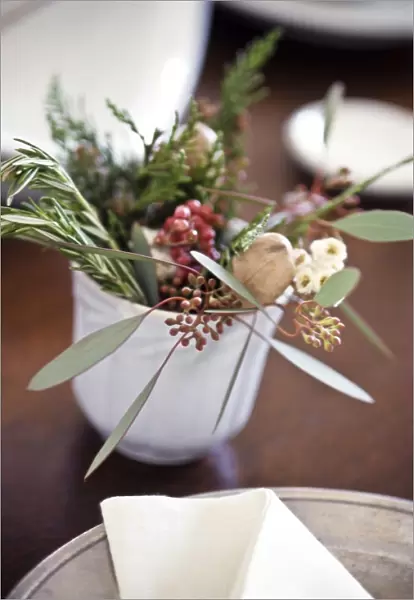 Table decoration of herbs, berries and greenery on small white cup credit: Marie-Louise