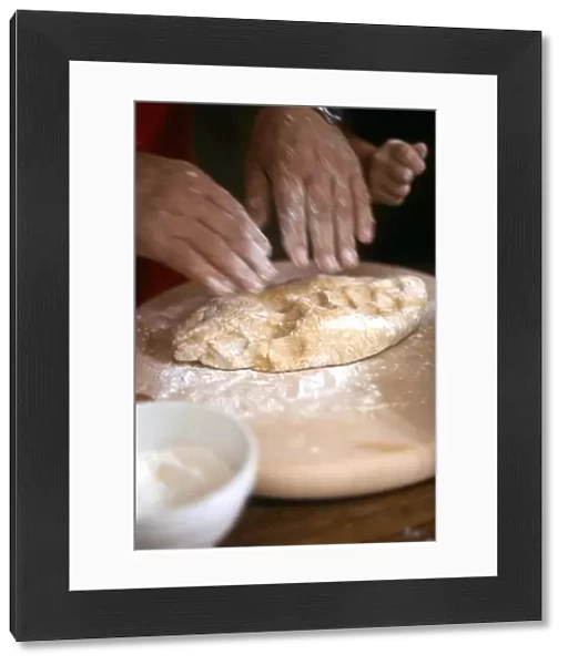 Man kneading and rolling pastry with little girl helping - hands only shown credit
