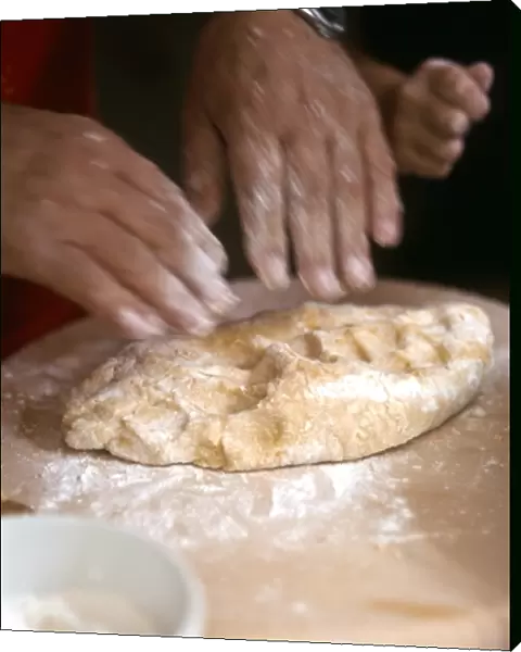Man kneading and rolling pastry with little girl helping - hands only shown credit