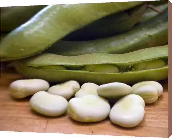 Freshly podded pale green broad beans on wooden surface credit: Marie-Louise Avery