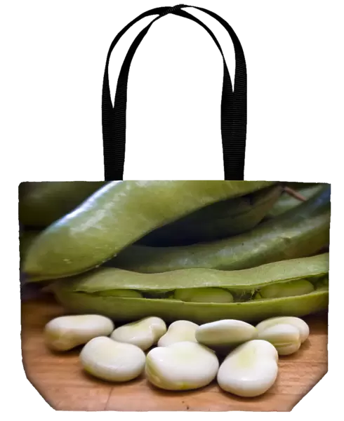 Freshly podded pale green broad beans on wooden surface credit: Marie-Louise Avery