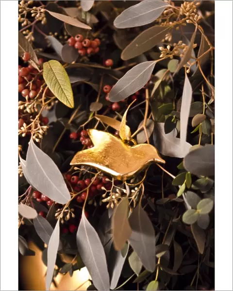 Detail of fireplace decorated for Christmas with massed mixed foliage and golden