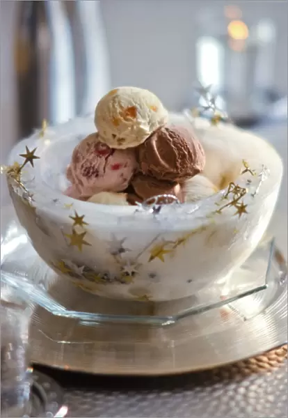 Ice bowl with stars holding balls of mixed icecreams for Christmas party credit