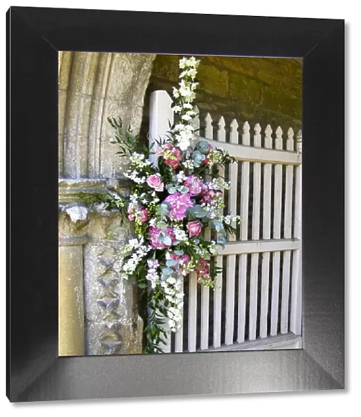 Flower arrangement decorating entrance to country church for summer wedding. credit