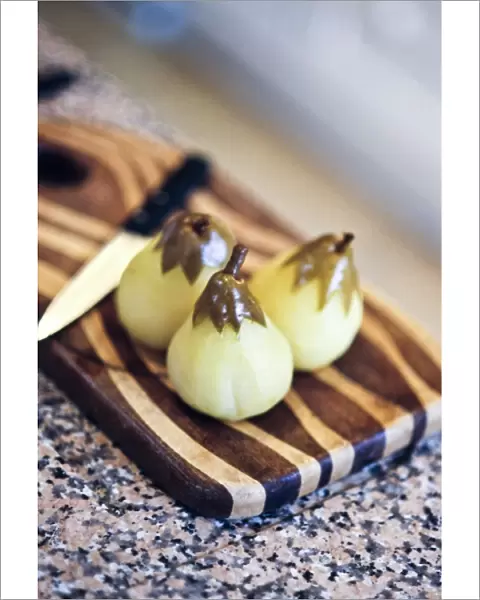 Peeled pears poached in vanilla sugar syrup on striped wooden board credit: Marie-Louise