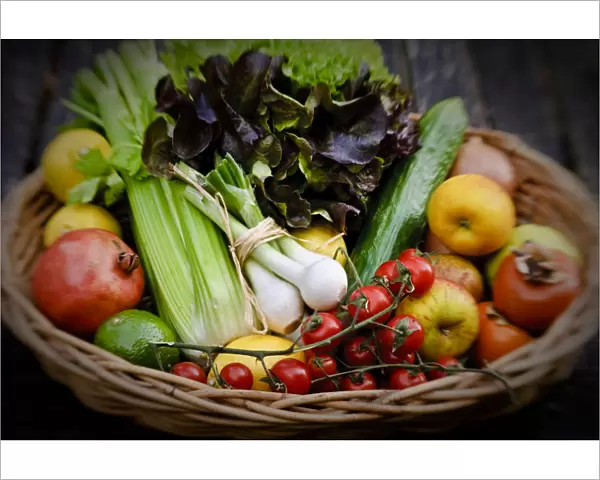Basket of fresh fruit and vegetables on red surface credit: Marie-Louise Avery