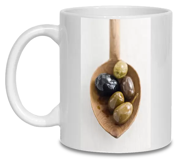 Selecion of various good whole olives on rustic wooden spoon credit: Marie-Louise