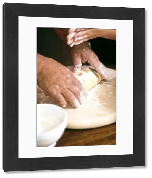 Chef kneading and rolling pastry with little girl helping - hands only shown credit