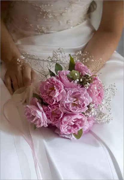 Posy style bridal bouquet held in hands on white satin dress credit: Marie-Louise