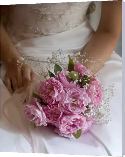 Posy style bridal bouquet held in hands on white satin dress credit: Marie-Louise