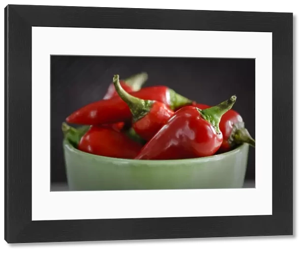 Shiny red chilli peppers in green bowl. Shorter depth of field. credit: Marie-Louise