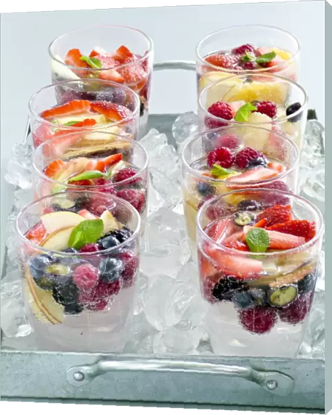Sparkling water with fresh fruit and berries in glasses sittin gon crushed ice