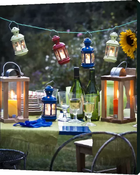 Table laid for a party outside on a summer evening, glasses of white wine with wine