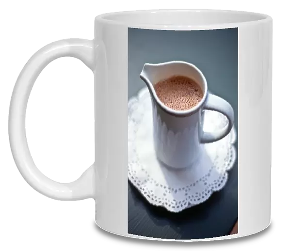 Jug of hot drinking chocolate on white paper lace doiley credit: Marie-Louise Avery