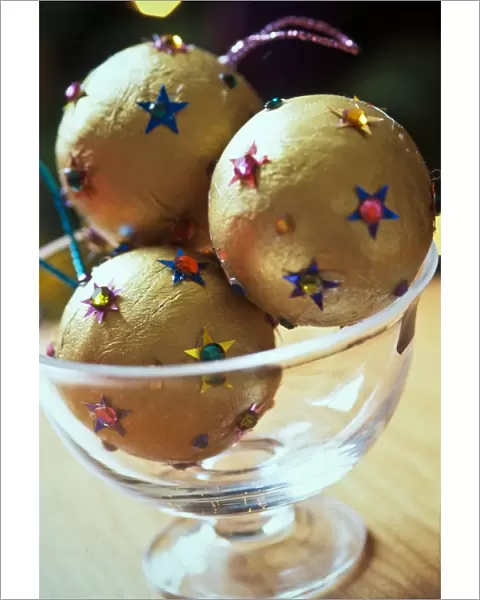 Gold christmas baubles with sequin stars in glass bowl as table centrepiece credit