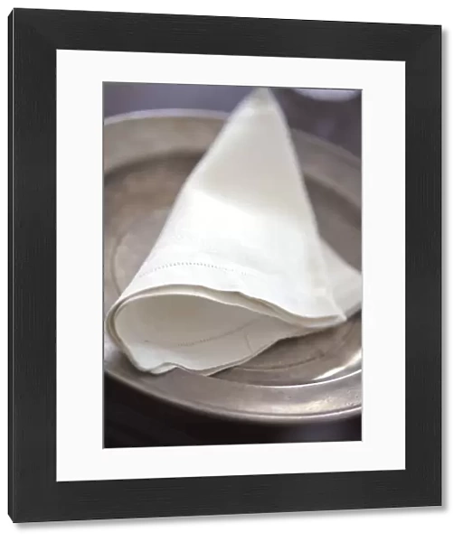 Folded linen napkin on pewter plate. credit: Marie-Louise Avery  /  thePictureKitchen