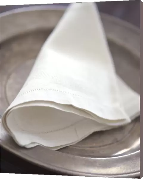 Folded linen napkin on pewter plate. credit: Marie-Louise Avery  /  thePictureKitchen