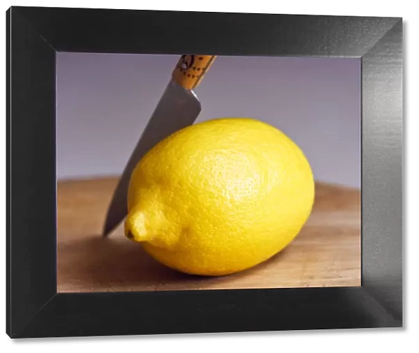 Whole fresh lemon with knife on cutting board credit: Marie-Louise Avery  /  thePictureKitchen