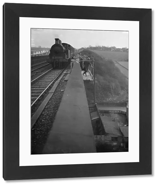 Railway workers stand on a scaffold frame on the edge of the viaduct as a steam engine