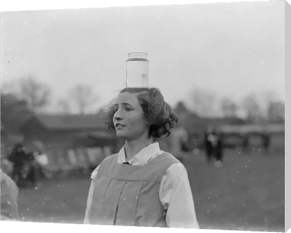 Girl balances a jar of water on her head. 1935