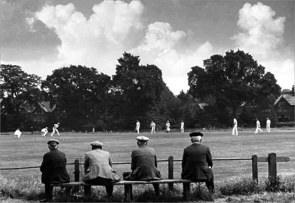 Elderly men sitting on a bench watching a local cricket match