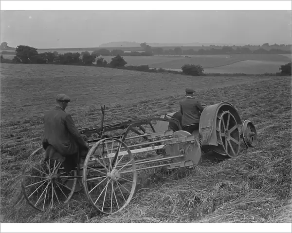Farmers using a new tractor drawn haymaking machine on a field in Farningham, Kent