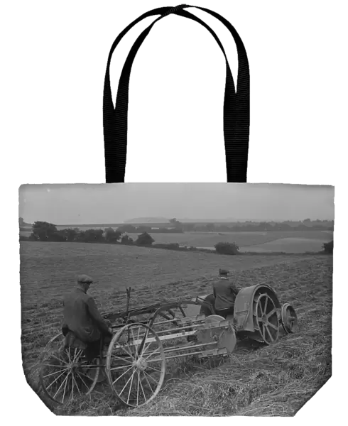 Farmers using a new tractor drawn haymaking machine on a field in Farningham, Kent