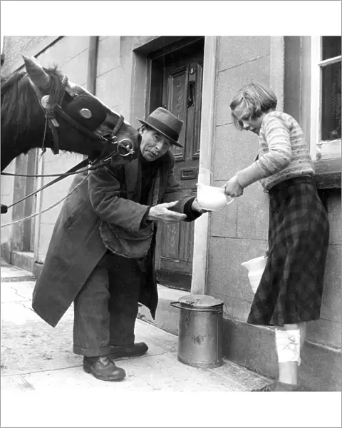 Old milkman and his affectionate horse, delivering milk from a churn in Monmouth, Wales
