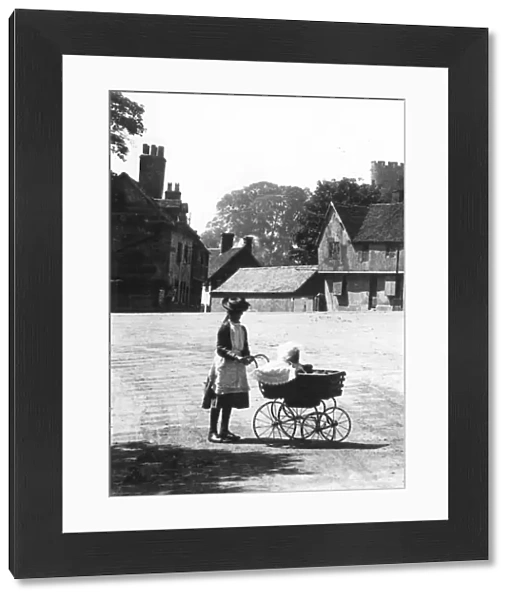 An older sister taking out the baby in a perambulator on a summers day walk taking