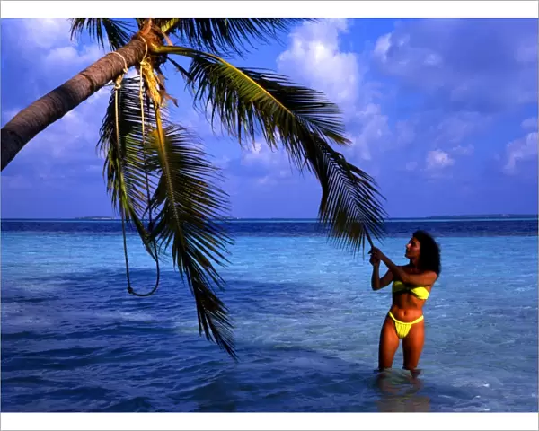 Little Bandos, an island ion the Maldives. With girl tugging at a palm tree. The