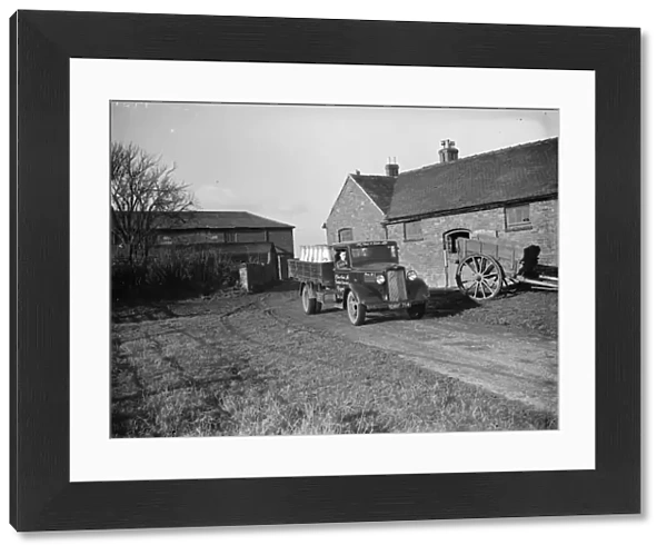 A milk lorry full of milk churns leaves the farmyard. 1937