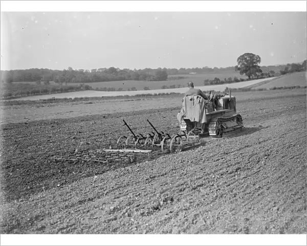 A farmer and his tank track tractor cultivates a field. 1935