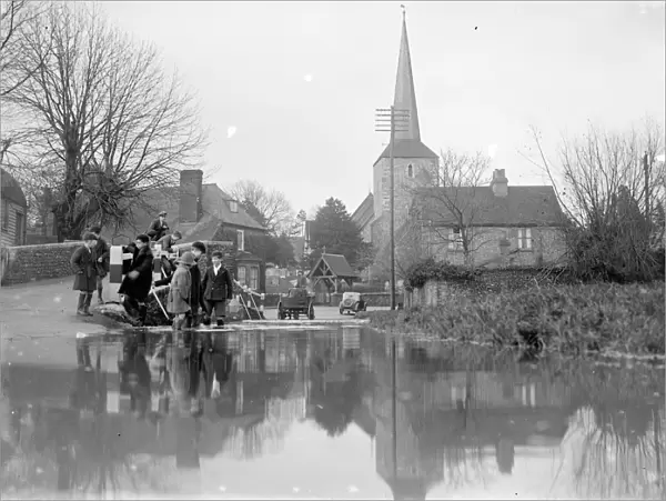 Children paddle in the flooded ford at Eynsford, Kent with St Martins church