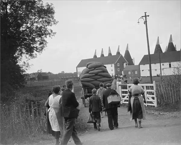 Hop pickers walking back to the oast houses with a loaded cart. 1935