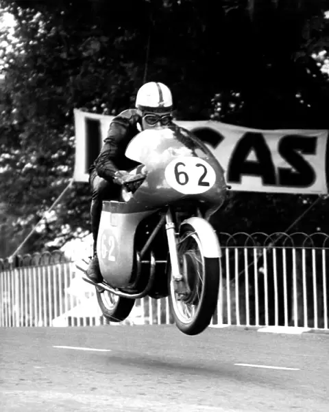 John Surtees MV machine is clear of the ground as he roars over Ballaugh Bridge