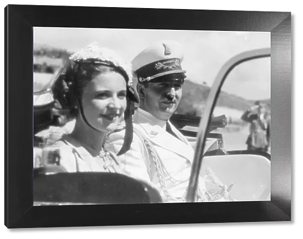 King Zog of Albania and his smiling young Queen, Geraldine, driving away after attending