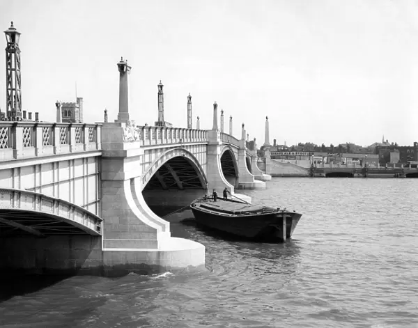 Watermen steering their barge underneath Lambeth Bridge, London