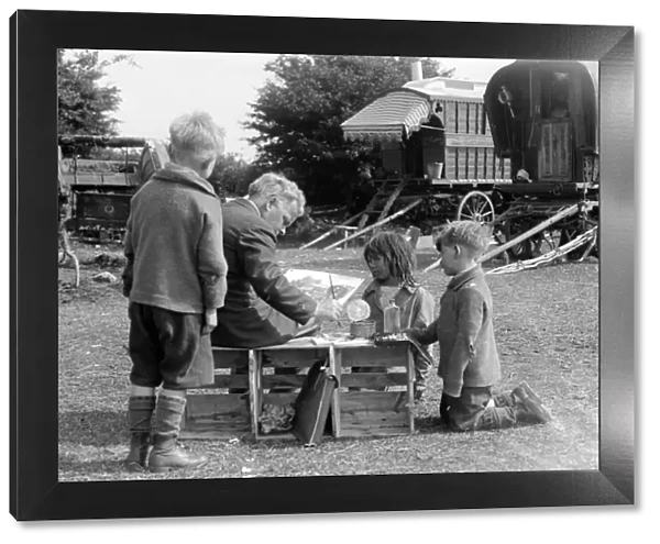 Gypsy children watching a man painting their caravan camp on Epsom Downs, Surrey