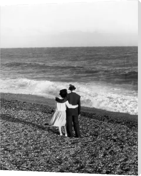Young couple with their arms round each other enjoing the seaside