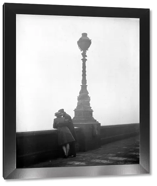 Couple arm in arm leaning over bridge in London in fog 1940s love couple romance