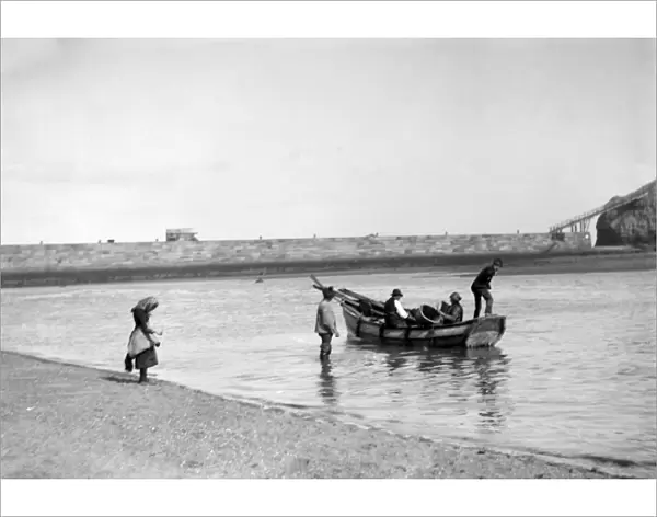 People out fishing from a Coble ( a locally made fishing boat ) at low tide, near