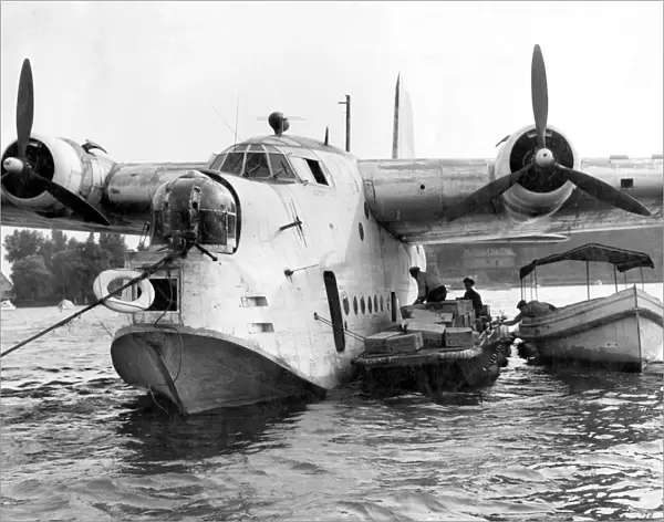 German workmen unload food from a British Royal Air Force flying boat, one of ten