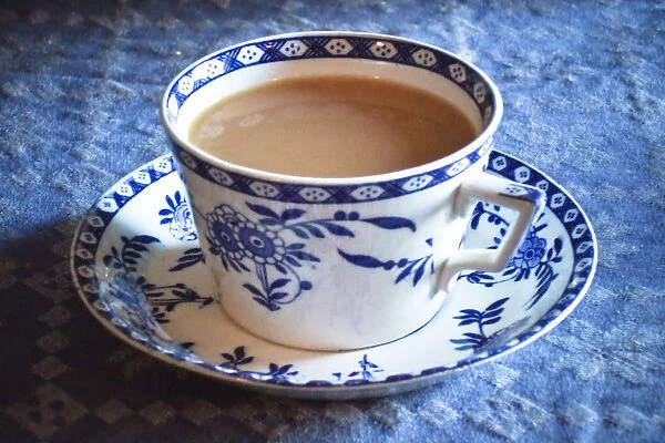 Antique blue and white cup and saucer of Indian tea with milk, on blue tablecloth