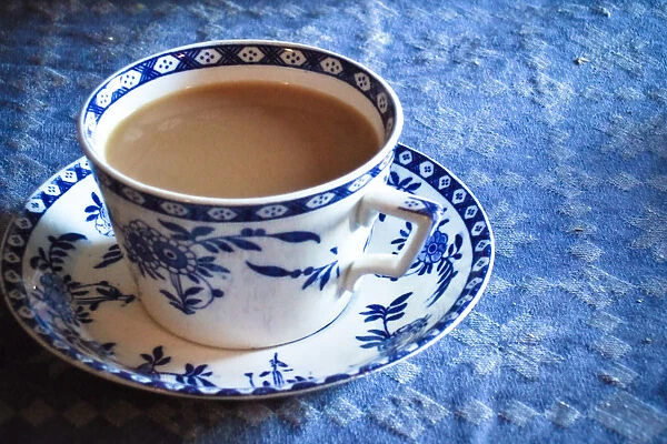 Antique blue and white cup and saucer of Indian tea with milk, on blue tablecloth