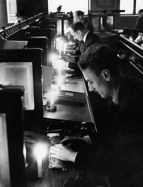 Bank clerks work by candlelight as Londons Electricity is Cut. Work went on by