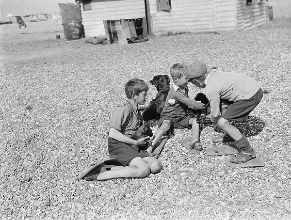 Boys playing on the shingle beach at Dungeness, Kent, wearing special wooden shoes