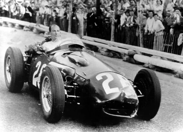 British racing driver Stirling Moss, 26, makes a lap of honour following his victory