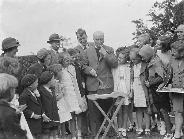 Canon Rs Greaves shows of a cake to children in Chislehurst, Kent